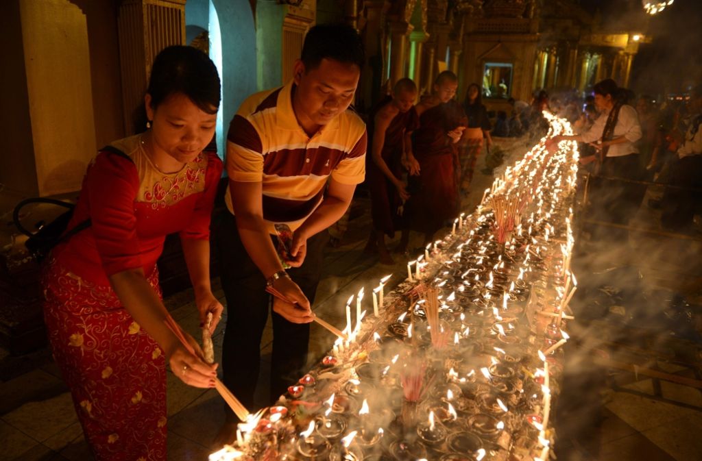 Gläubige und Mönche entzünden gemeinsam Kerzen. Foto: AFP