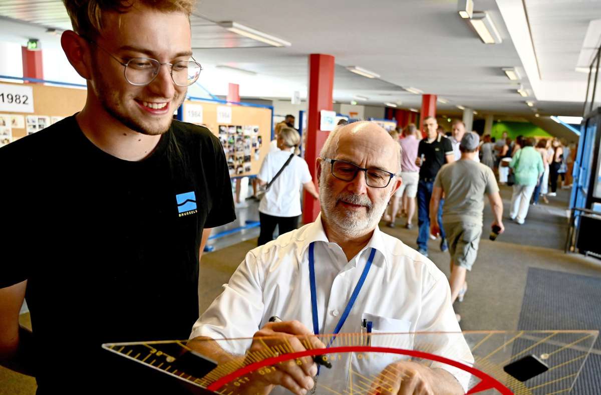 Ex-Schulleiter Bernhard Joos (rechts) signiert ein Riesen-Geodreieck, das sich ein ehemaliger Schüler als Andenken gesichert hat. Foto:  