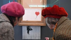 Besucher betrachten das geschredderte Banksy-Bild in Baden-Baden. Foto: dpa