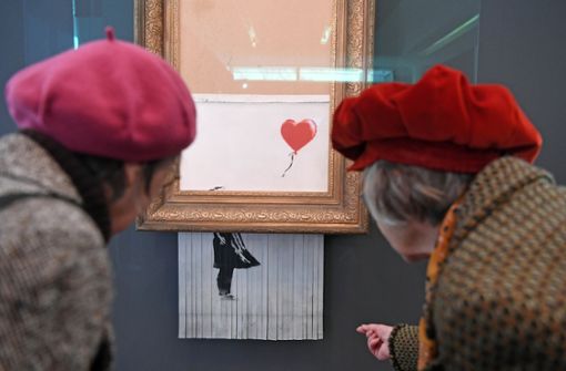 Besucher betrachten das geschredderte Banksy-Bild in Baden-Baden. Foto: dpa