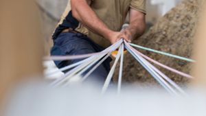 Ein Bauarbeiter hält ein Bündel Leerrohre in der Hand, durch die Glasfaserkabel gezogen werden sollen. Foto: dpa/Guido Kirchner