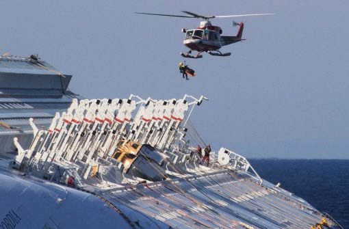Mitarbeiter eines Rettungsteams bringen am 23.02.2012 mit dem Hubschrauber aus dem Wrack der Costa Concordia geborgene Opfer des Schiffsunglücks auf die Insel Giglio. Foto: ANSA