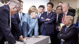 Angela Merkel stützt sich auf den Tisch, Donald Trump verschränkt die Arme. Dieses Bild vom G7-Gipfel in Kanada macht im Internet die Runde. Foto: German Federal Government
