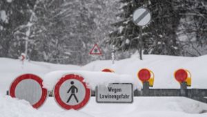 Schilder weisen an einer gesperrten Straße in Bayern auf Lawinengefahr hin. Foto: dpa/Lino Mirgeler