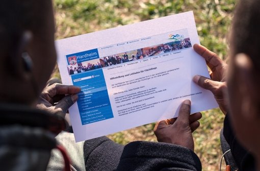 Zwei Flüchtlinge lesen in Hardheim eine ausgedruckte Version des Leitfadens mit Benimmregeln für Flüchtlinge, den die Stadtverwaltung unter Kritik auf ihrer Internetseite veröffentlicht hat. Foto: dpa