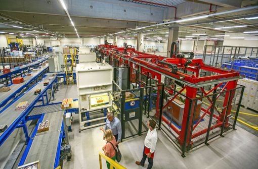 Förderbänder versorgen die Packroboter in den roten Käfigen permanent mit den Waren, die die Filialen bestellt haben. Foto: Roberto Bulgrin