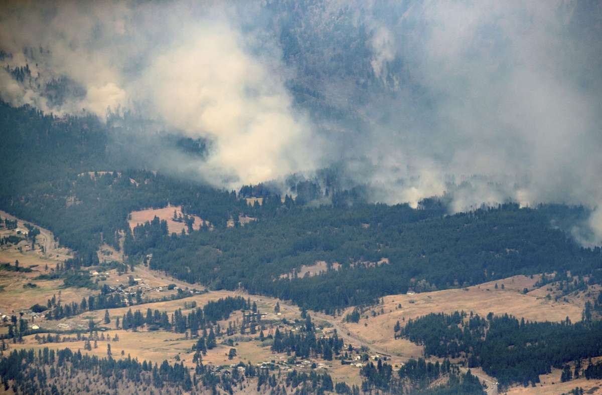 Rauch steigt über einem Wald in den Bergen nördlich von Lytton, British Columbia.