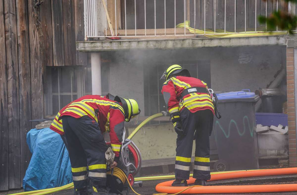 Zwei Einsatzkräfte der Feuerwehr bekämpfen den Brand in einem Wohnhaus in Aichwald.