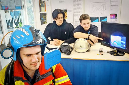 Die Abiturienten Tom (mit Helm),  Thai Son und Justin  des Berufsschulzentrums Leonberg tüfteln am Feuerwehrhelm der Zukunft. Foto: factum/Granville