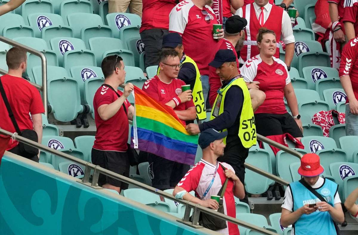 Zwei Ordner wollen diesen dänischen Fans offenbar eine Regenbogen-Fahne abnehmen.