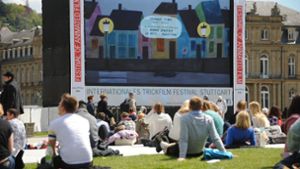 Bei schönem Wetter sitzen zahlreiche Menschen auf dem Schlossplatz vor der Leinwand des Trickfilmfestivals in Stuttgart. Foto: dpa