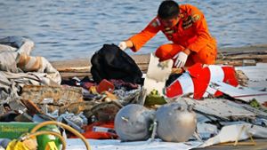 Ein Mitarbeiter der indonesischen Such- und Rettungsbehörde inspiziert Trümmerteile und Fundstücke des abgestürzten Passagierflugzeugs Foto: AP