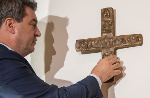 Markus Söder, Bayerischer Ministerpräsident (CSU), hängt ein Kreuz im Eingangsbereich der bayerischen Staatskanzlei auf. Foto: dpa