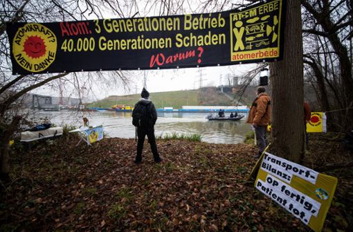 Atomkraftgegner beobachten, wie auf der anderen Seite des Neckars der Castortransport aus Obrigheim am Kernkraftwerk in Neckarwestheim vor Anker geht. Foto: dpa