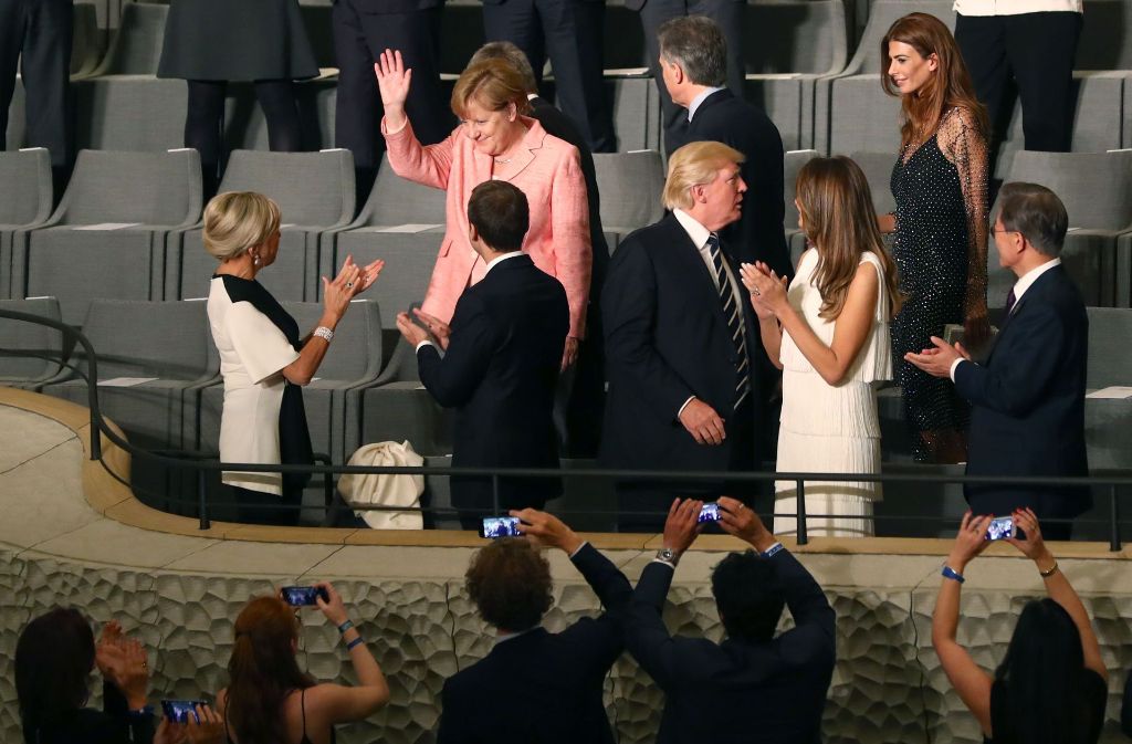 Bundeskanzlerin Angela Merkel wird klatschend vom französischen Präsidenten Emmanuel Macron und seiner Frau Brigitte Trogneux begrüßt.