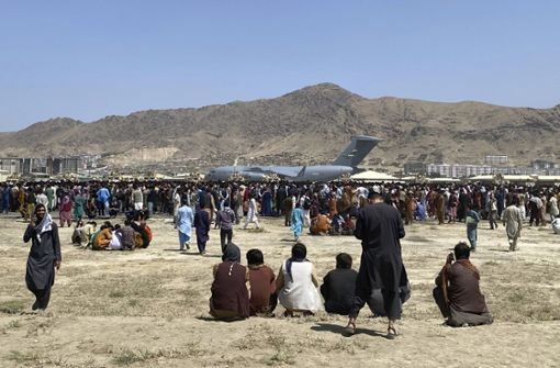 Hunderte Menschen versammeln sich in der Nähe eines US-Transportflugzeugs. Foto: dpa/Shekib Rahmani