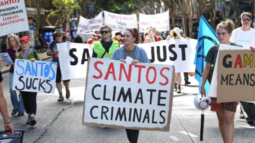 Demonstranten halten Plakate während einer Protestaktion der Extinction Rebellion gegen das Energieunternehmen Santos in Brisbane. Foto: dpa/Darren England
