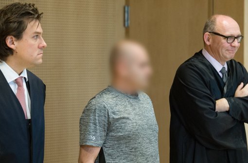 Der mutmaßliche Schleuser Muhammad H. steht zwischen seinen beiden Anwälten zum Prozessauftakt in einem Verhandlungssaal des Landgerichts in Frankfurt (Oder). Foto: dpa