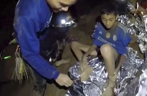 Auf diesem Videostandbild der Thai Navy Seals ist ein Jugendlicher einer Fußballmannschaft, die in einer Höhle in Thailand eingeschlossen ist, zu sehen, der von einem Navy Seal versorgt wird. Foto: Royal Thai Navy Facebook Page/AP