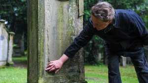 Restauratorin Juliane Weigele zeigt am Freitag, an welche Stellen dieser   Grabstein auf dem Hoppenlaufriedhof besonders gelitten hat. Foto: Michele Danze