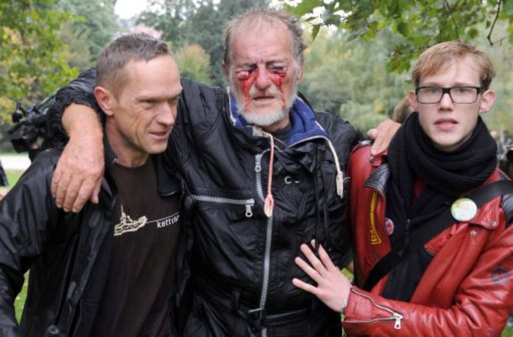 Zwei Männer stützen im Schlossgarten den verletzten Dietrich Wagner. Mittlerweile ist klar, dass der 66-jährige Renter nahezu blind bleiben wird. Foto: dpa