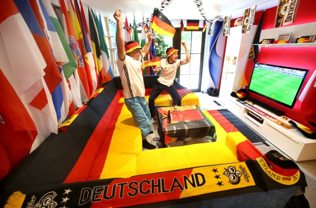 Die beiden Fußballfans Stefan (r.) und Wolla jubeln in ihrem dekorierten Wohnzimmer in Haan.