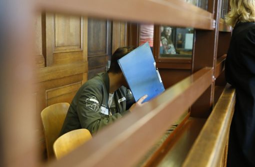 Der Angeklagte versteckt sein Gesicht hinter einem Ordner. Foto: Getty Images Europe
