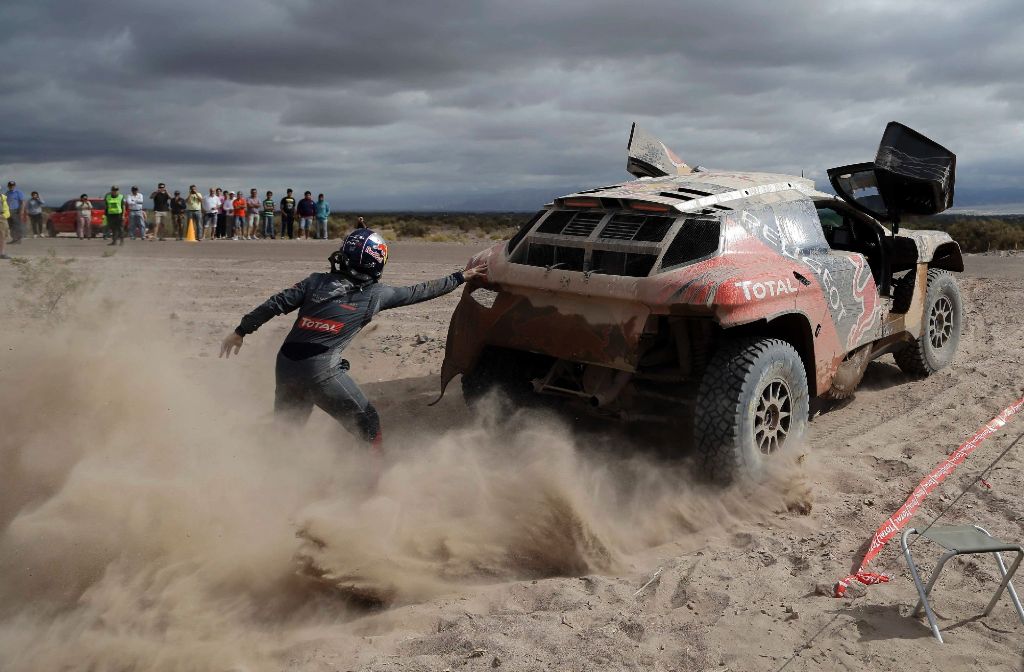 Peugeot-Fahrer Cyril Despres schiebt sein Auto an. Die Rallye Dakar ist brandgefährlich – und sie produziert spektakuläre Bilder. Eine Auswahl der Rallye 2016 zeigen wir in der folgenden Fotostrecke.