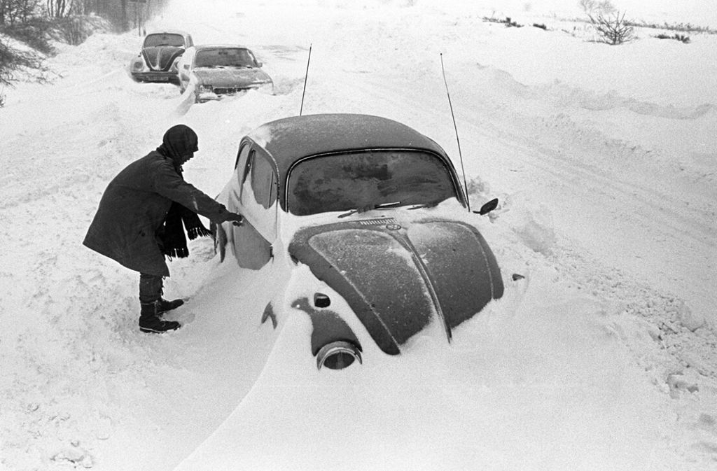 Ein Autofahrer steht neben seinem am Straßenrand im Schnee stecken gebliebenen VW-Käfer, aufgenommen bei Cuxhaven am 31. Dezember 1978. Der Temperatursturz vom 29. Dezember 1978 führte in Norddeutschland, dem Norden der DDR, Dänemark und Südschweden zu einem Schneechaos.