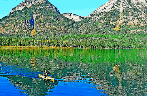 Über das glasklare Wasser des Upper Waterton Lake gleitet ein Kajakfahrer. Foto: Riepl