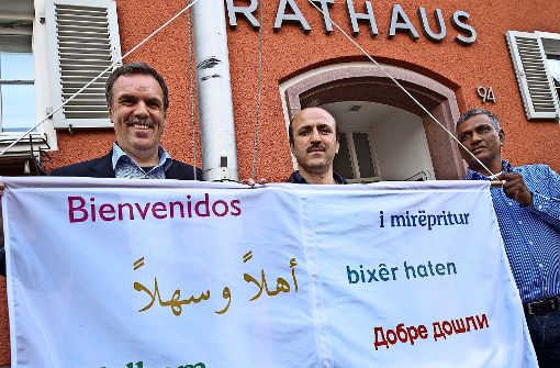 Der Bürgermeister Hans-Rudi Bührle, Ramadan Abdullah und Shinder Pal ziehen die Fahne auf. Foto: Michael Steinert