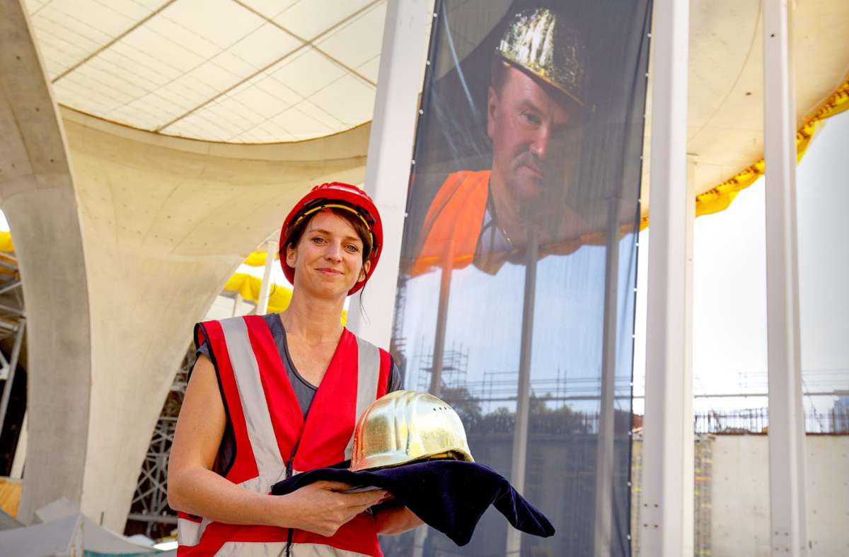 Die Künstlerin Nina Nielebock vor ihrer Fotografie „Der Mann mit dem Goldhelm“ an  einer Kelchstütze des Bahnhofs.