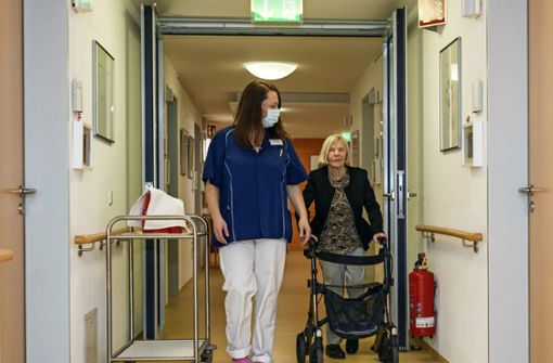 Sandra Wutzler, Leiterin einer Pflegestation im Haus am Brunnen in Maichingen, begleitet eine Bewohnerin durchs Haus. Foto: Eibner/Ioannou