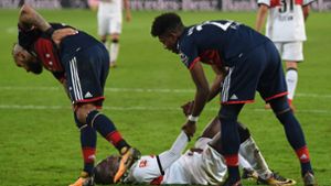 Chadrac Akolo liegt nach seinem verschossenen Elfmeter enttäuscht auf dem Rasen, während die Bayern-Spieler Arturo Vidal (links) und David Alaba den VfB-Stürmer trösten. Foto: Bongarts