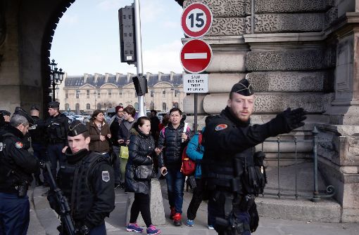 Museums-Besucher verlassen am Freitag begleitet von bewaffneten Polizisten den Louvre in Paris. Foto: AP