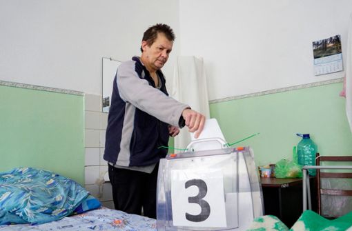 Ein Mann in einem Krankenhaus von Berdyansk wählt mit einer mobilen Wahlurne. Foto: AFP/STRINGER