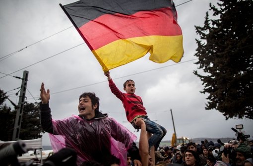 Flüchtlinge in Idomeni schwenken die deutsche Flagge. Foto: dpa