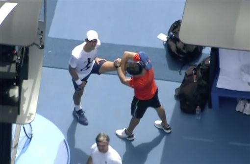 Auf diesem Foto, das aus Luftaufnahmen stammt, dehnt sich Tennisstar Novak Djokovic (links) während einer Trainingseinheit mit Mitarbeitern auf dem Tennisplatz. Foto: dpa/Uncredited