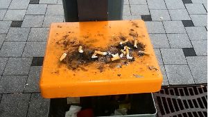 Auf den  orangefarbenen Mülleimerdeckeln stapeln sich Zigarettenkippen. Foto: privat