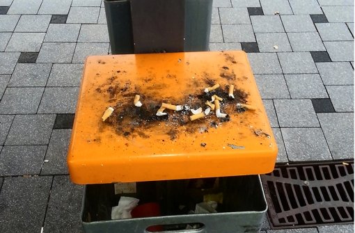 Auf den  orangefarbenen Mülleimerdeckeln stapeln sich Zigarettenkippen. Foto: privat
