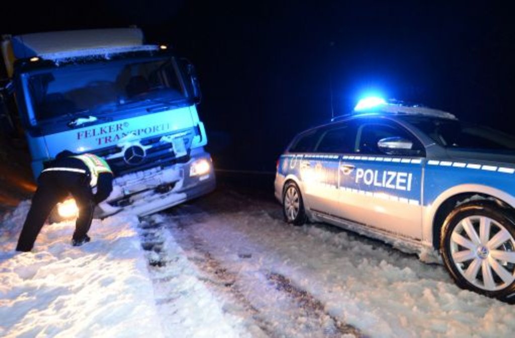 Ein Polizeifahrzeug steht am Mittwoch auf der B31 im Höllental bei Hinterzarten (Baden-Württemberg) neben einem Lkw, der im Graben steckt. Starker Schneefall hat im Schwarzwald für ein Verkehrschaos gesorgt.