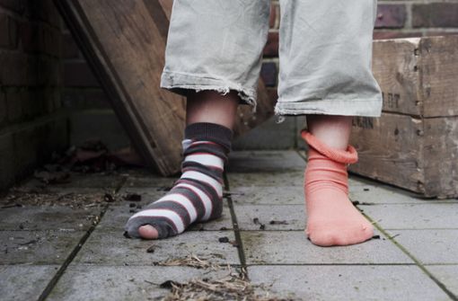 Ein zehn Jahre altes Mädchen steht in Hamburg in abgetragener Kleidung ohne Schuhe in einem Hinterhof. Foto: dpa