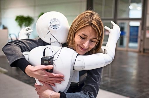 Körperkontakt erwünscht: Eine Mitarbeiterin des französischen Roboterherstellers Aldebaran umarmt auf dem Messegelände der Cebit Hannover einen Roboter. Foto: dpa