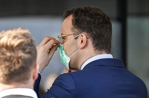 Vor dem Besuch der Düsseldorfer Uniklinik erhält Gesundheitsminister Jens Spahn eine professionelle Schutzmaske. Foto: AP/Martin Meissner