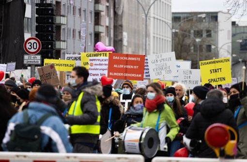 Die Teilnehmer einer Demonstration gegen die Corona-Maßnahmen stehen vor dem Start und tragen dabei Schilder. Foto: dpa/Philipp von Ditfurth