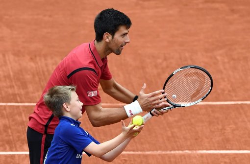 Novak Djokovic zieht ins Halbfinale ein, und feiert nach dem Spiel mit einem Balljungen. Foto: AFP