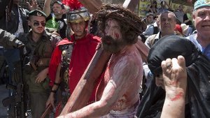 Sie schleppen große Holzkreuze und laufen den Leidensweg Jesu ab: Weltweit erleben Christen den Karfreitag hautnah mit. Foto: dpa