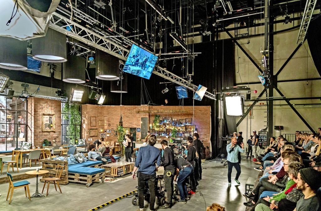 Schauspieler und  Kameraleute gehen auf Position, während der Anheizer (rechts) die Stimmung im Studio hochtreibt.
