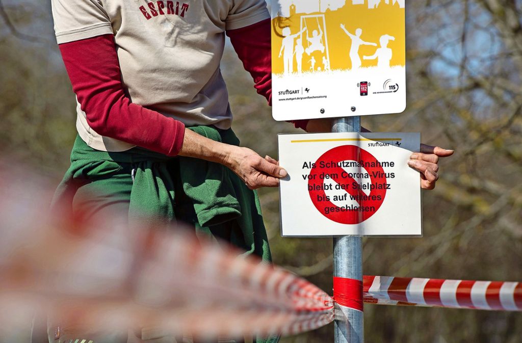 Eine Mitarbeiterin befestigt ein Warnschild auf dem Spielplatz am Killesberg.Foto: Lichtgut/Leif Piechowski