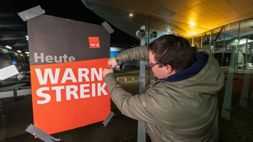 Streikende hängen Plakate mit der Aufschrift Warnstreik bei der Lufthansa Technik auf. Mit erneuten Warnstreiks gleich mehrerer Berufsgruppen legt die Gewerkschaft Verdi am Donnerstag und Freitag wichtige Teile des deutschen Luftverkehrs lahm. Foto: Bodo Marks/dpa